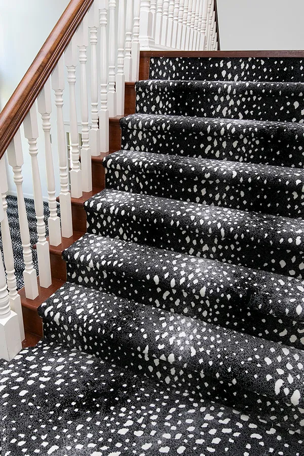 White and wooden banister with patterned stair runner 
