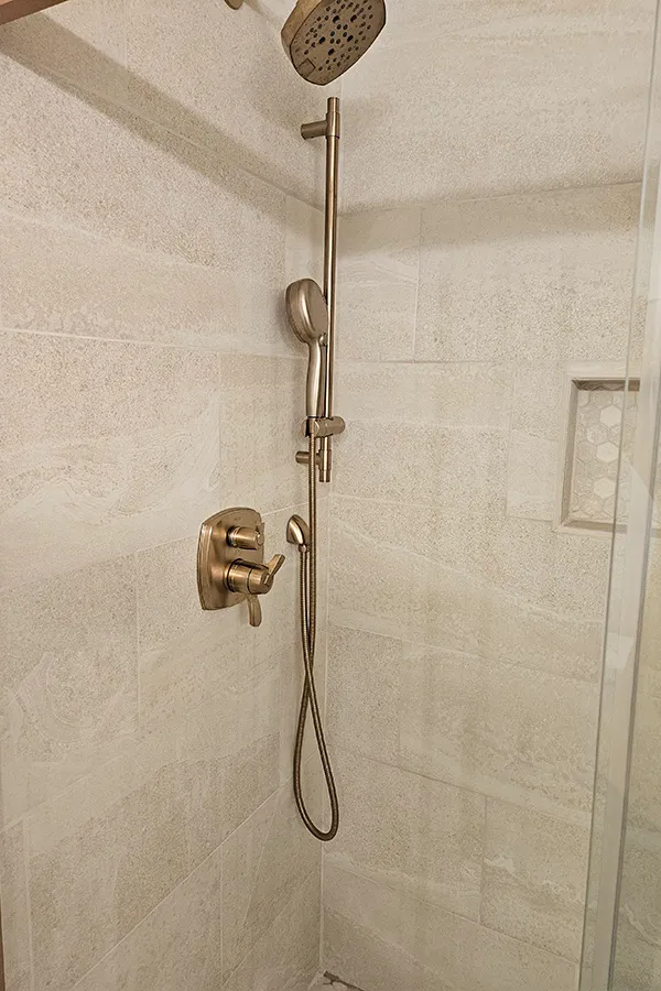 Tiled glass walk in shower with brass faucet